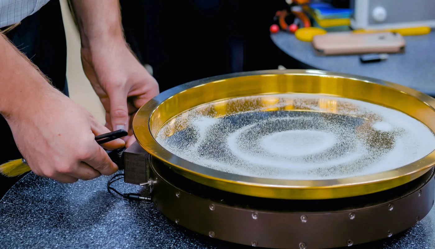 A cimática, termo derivado do grego kyma (onda), é o estudo das formas visíveis criadas pela vibração do som. Embora pareça algo moderno, na verdade é uma área que atravessa séculos e conecta ciência, arte, filosofia e espiritualidade. A ideia central é simples: quando uma superfície ou substância é submetida a uma frequência sonora, ela responde criando padrões geométricos. Esses padrões não são aleatórios, eles seguem leis universais que expressam a ordem do universo, especialmente a lei da ressonância.